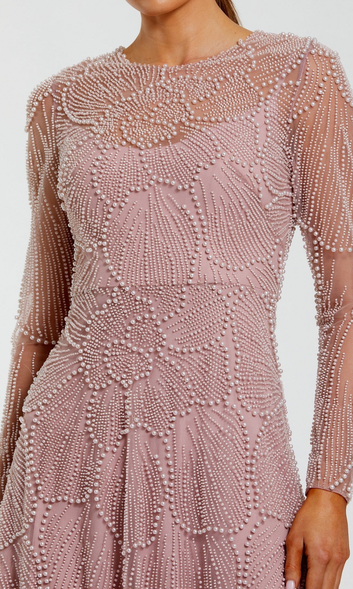 A person wearing the Mac Duggal 69012 long formal dress, showcasing light pink fabric adorned with intricate beaded embellishments in elegant floral and geometric patterns.